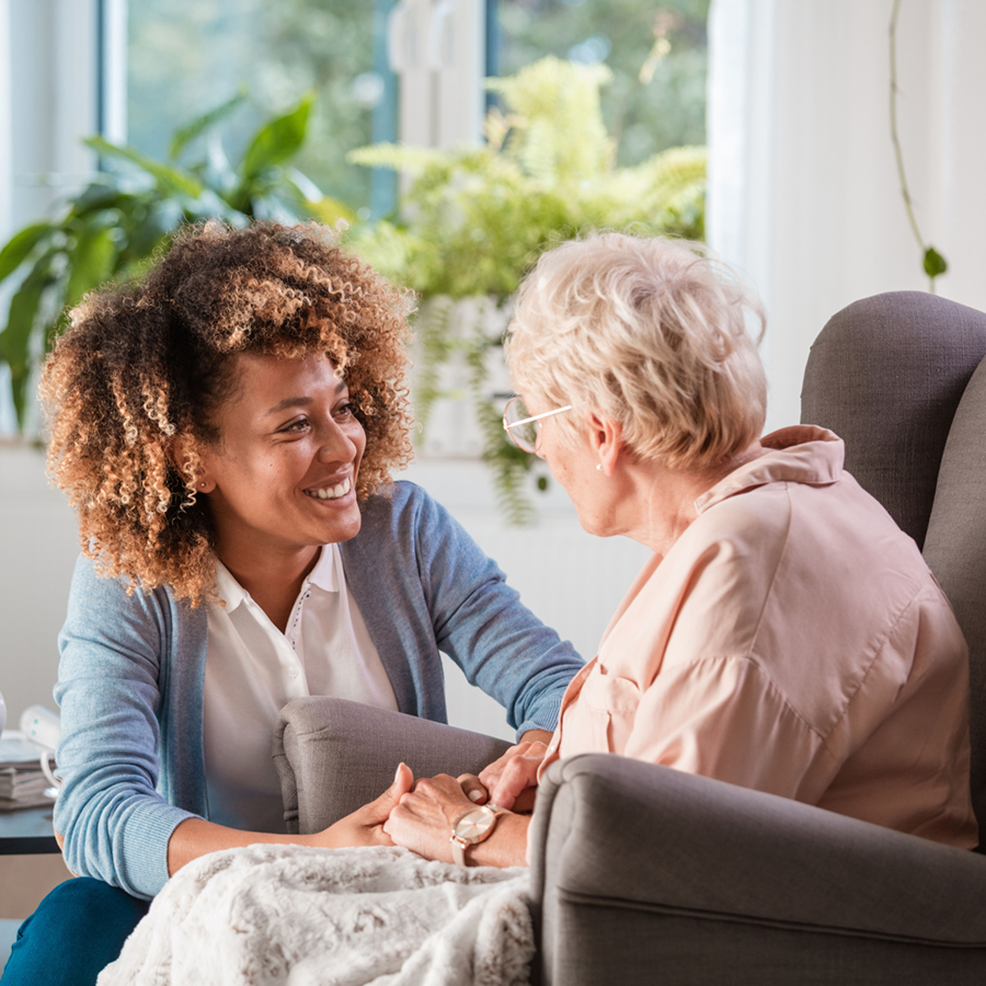 a woman holding the hand of an elderly woman while talking to her