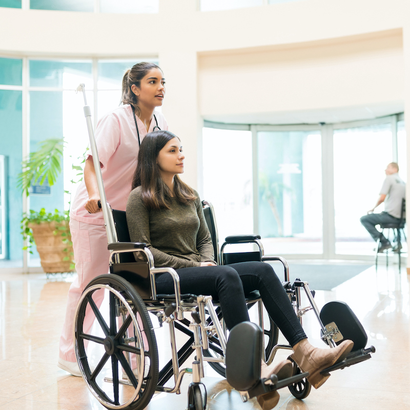 image of a nurse pushing a woman in a wheel chair outside 